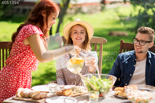 Image of happy friends having dinner at summer garden party