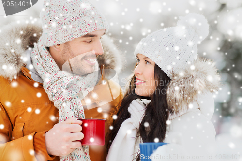 Image of happy couple with tea cups over winter landscape