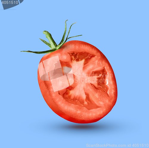 Image of half tomato over a blue background