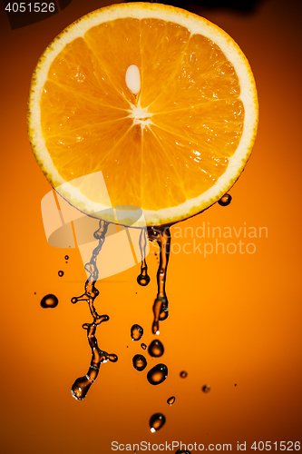 Image of Orange slice and splash of juice isolated on color background