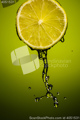 Image of Juicy lime and drops of juice isolated on green blackground in studio.