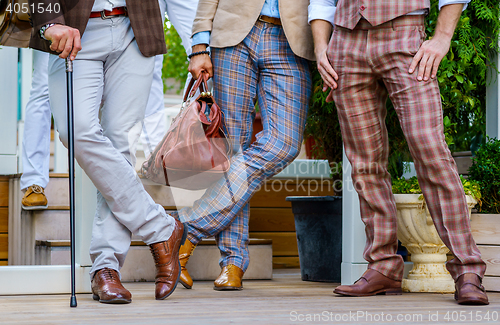 Image of Stylish men in trendy suit with a walking stick and  leather valise stand on the terrace in summer