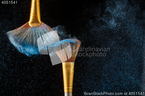 Image of Two brushes and blue feathered shadows at black background