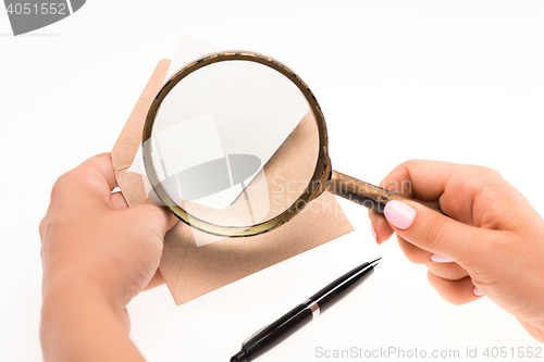 Image of The female hands with envelope with magnifying glass on white background