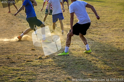 Image of Young boys playing football game on the sunset