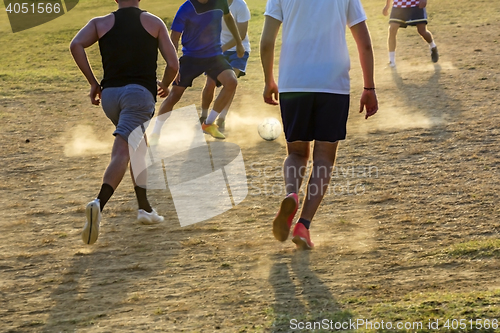 Image of Young boys playing football game on the sunset