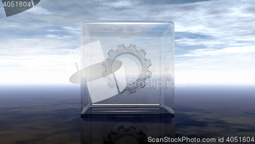 Image of gear wheel in glass cube on reflective surface - 3d rendering