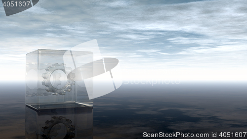 Image of gear wheel in glass cube on reflective surface - 3d rendering