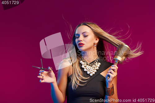 Image of Female stylist standing with hairdresser\'s accessories