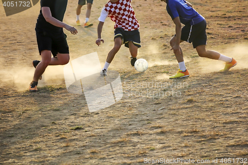 Image of Young boys playing football game on the sunset