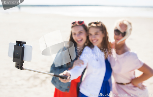 Image of women with selfie stick and smartphone on beach