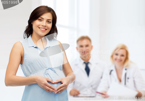 Image of happy pregnant woman making heart gesture on belly