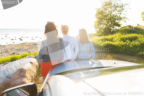 Image of happy teenage girls or women near car at seaside