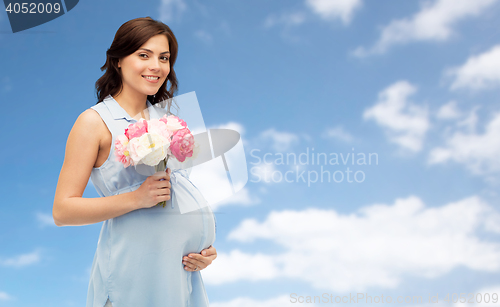 Image of happy pregnant woman with flowers over blue sky