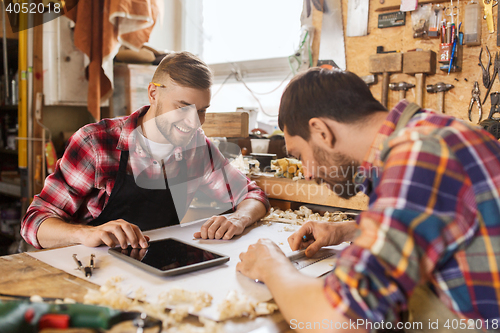 Image of workmen with tablet pc and blueprint at workshop