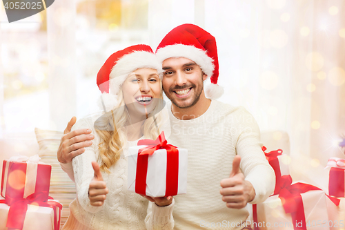 Image of happy couple with christmas gifts and thumbs up