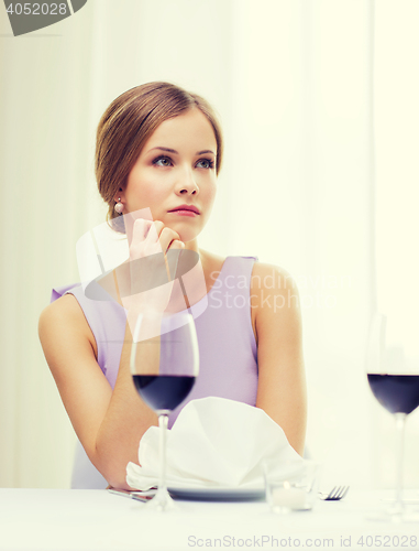 Image of upset woman with glass of whine waiting for date