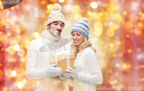 Image of smiling couple in winter clothes with gift box