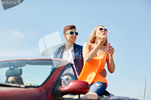 Image of friends driving in car and blowing bubbles