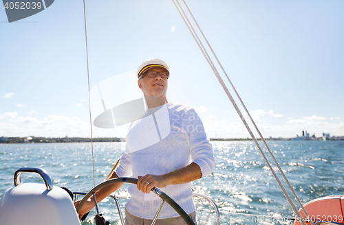 Image of senior man at helm on boat or yacht sailing in sea