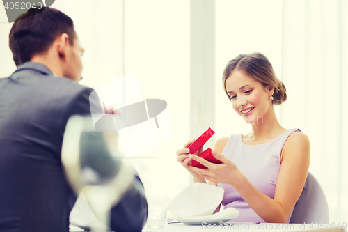 Image of excited young woman looking at boyfriend with box