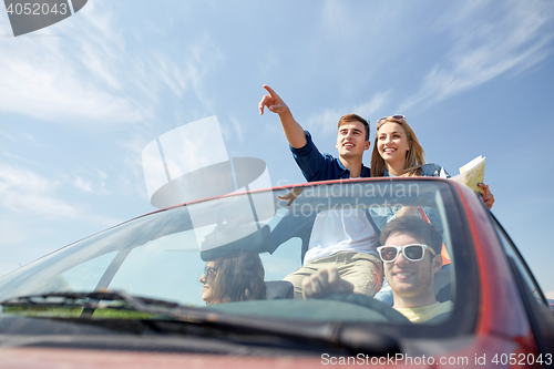 Image of happy friends driving in cabriolet car