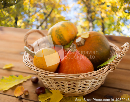 Image of close up of pumpkins in basket on wooden table 