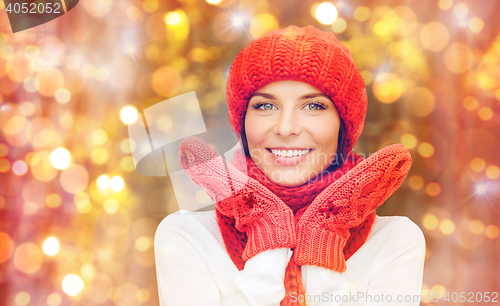 Image of happy woman in hat, scarf and mittens over lights