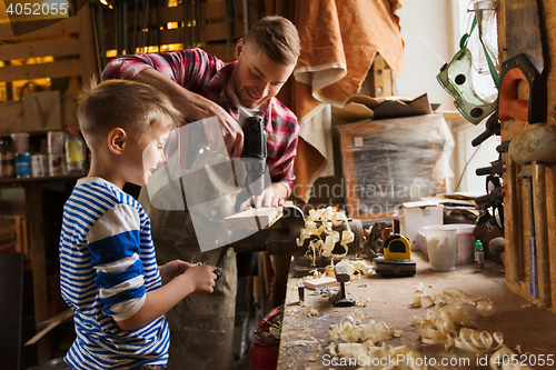 Image of father and son with drill working at workshop