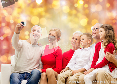 Image of smiling family with camera over christmas lights