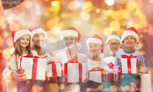 Image of happy family in santa hats with gift boxes