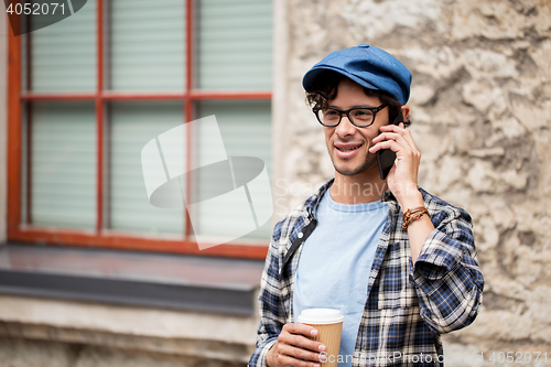 Image of man with coffee calling on smartphone in city