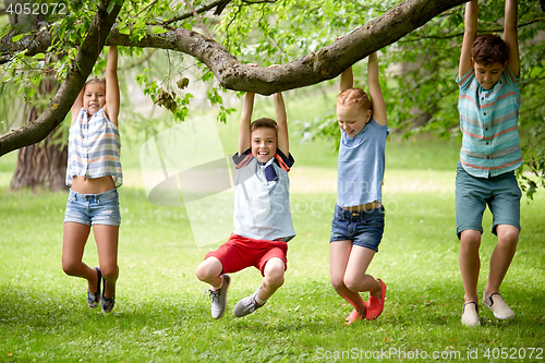 Image of happy kids hanging on tree in summer park