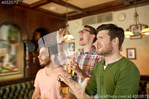 Image of friends with beer watching sport at bar or pub