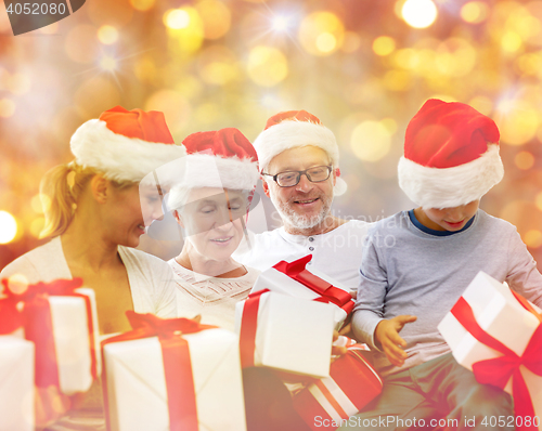 Image of happy family in santa hats with gift boxes