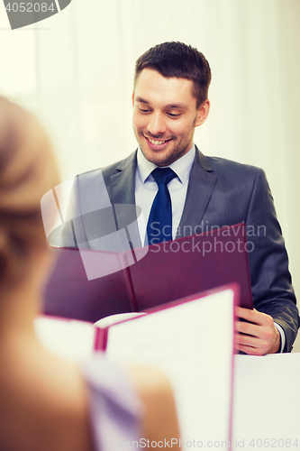 Image of smiling young man looking at menu at restaurant