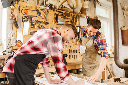 Image of carpenters with ruler and blueprint at workshop