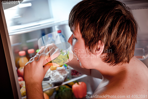 Image of Hungry man holding a sandwich in his hands and standing next to 