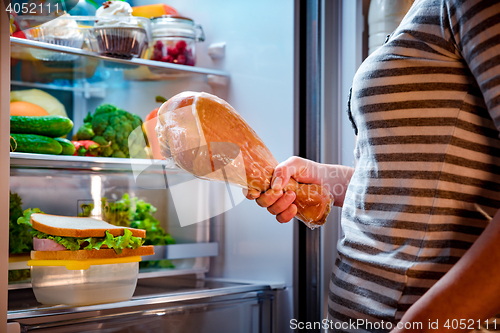 Image of Hungry Woman holding a turkey leg in his hands and standing next