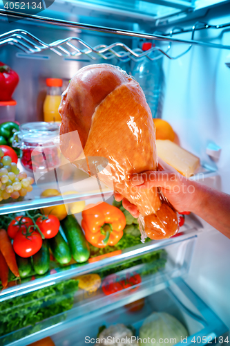 Image of Human hands reaching for turkey leg food at night in the open re