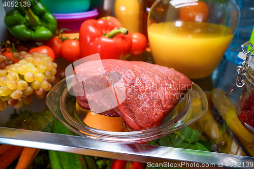 Image of Fresh raw meat on a shelf open refrigerator