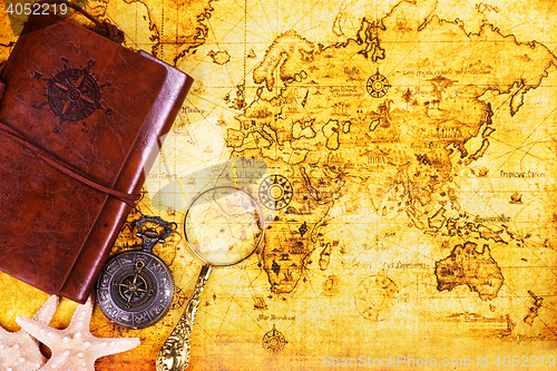 Image of old notebook, loupe and compass on the map