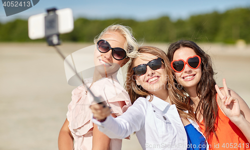 Image of group of smiling women taking selfie on beach