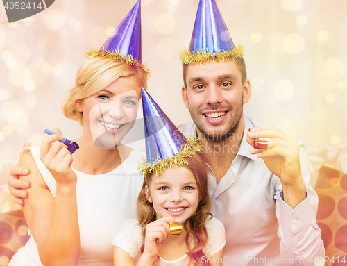 Image of smiling family in blue hats blowing favor horns