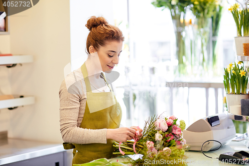 Image of smiling florist woman making bunch at flower shop
