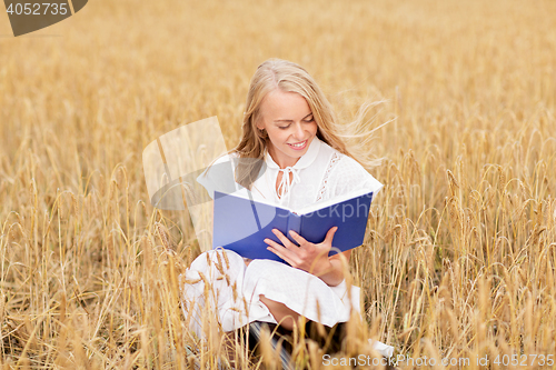 Image of smiling young woman reading book on cereal field