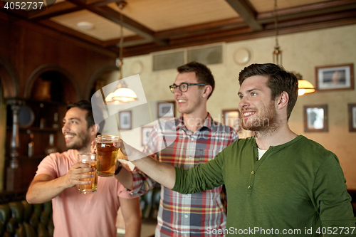 Image of happy male friends drinking beer at bar or pub