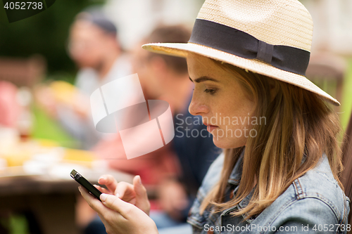 Image of woman with smartphone and friends at summer party