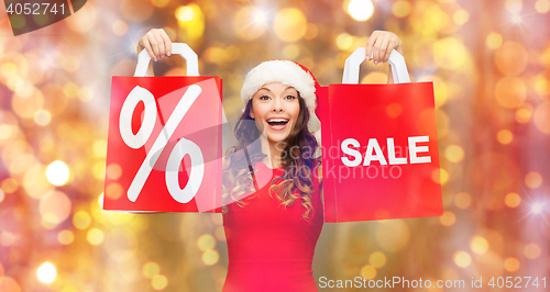 Image of happy woman in santa hat with red shopping bags