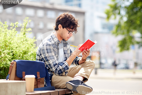 Image of man with notebook or diary writing on city street